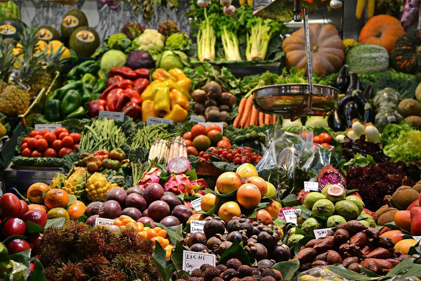 A produce market stall with fruit and vegetables. The stall’s own labels are not Meridian prices or products.