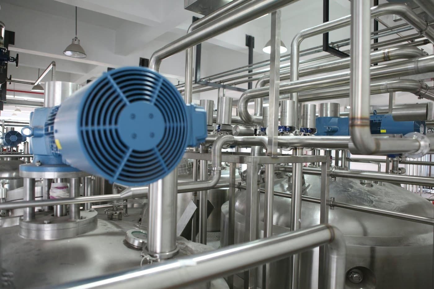 Stainless steel processing equipment in an industrial interior, shown as a study of materials and manufacturing settings.